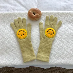 Détail en gros plan de gants d'hiver tricotés confortables avec un joli patch smiley.