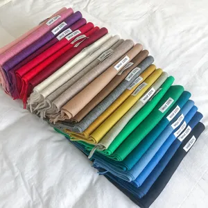 Primer plano detallado de varias bufandas de lana con flecos de colores apiladas ordenadamente.