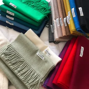 Vista detallada de bufandas de lana multicolores con flecos y etiquetas de material.