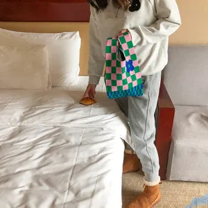 Vue détaillée du sac à main en tricot à carreaux roses et verts avec joli motif de fleurs.