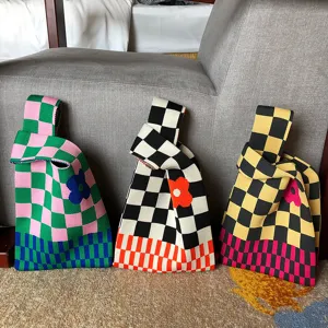 Sac à main tricoté à motif de carreaux avec des fleurs vibrantes et une poignée confortable.