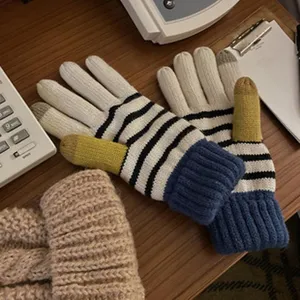 Nahaufnahme stilvoller Winter-Strickhandschuhe mit Streifenmuster und bunten Fingerspitzen.