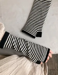 Nahaufnahme von schwarz-weiß gestreiften Strick-Fingerlosen Handschuhen, Winter Accessoire.