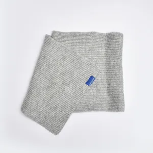 Knit neck warmer detail view, soft gray ribbed fabric close-up with blue brand label.