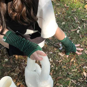 Primer plano detallado de guantes de punto sin dedos a rayas verdes y negras al aire libre.