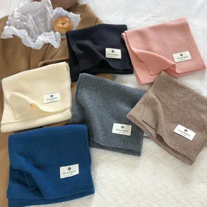 Detailed view of soft winter knit scarf texture and woven label, cozy solid color design.
