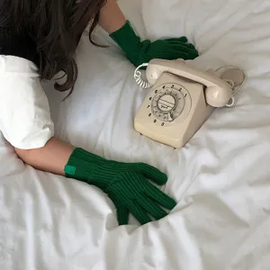 Primer plano de los guantes de punto verde que destacan la textura suave y el ajuste.
