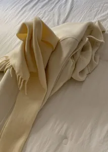 Vista dettagliata di una sciarpa morbida tinta unita con frange su letto, stile invernale.