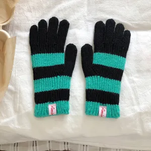 Close-up van zwart met turquoise gestreepte gebreide handschoenen winter accessoire detail.
