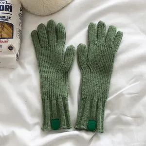 Vista detallada de guantes de invierno de punto verde con textura suave y etiqueta.