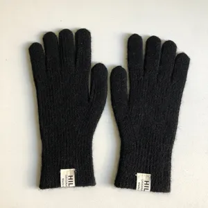 Vista dettagliata di guanti invernali neri lavorati a maglia con etichetta di marca.