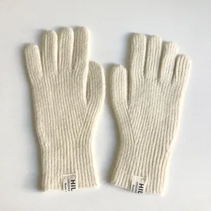 Dettaglio ravvicinato di caldi e accoglienti guanti invernali lavorati a maglia beige.