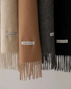 Vista detallada de bufandas de lana pura con textura suave, flecos delicados y colores sólidos.