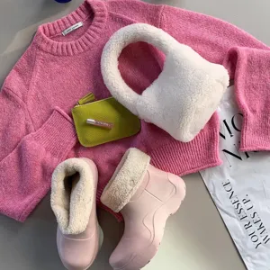 Sac à main douillet en peau d'agneau d'hiver avec pull en tricot rose et jolies bottes.