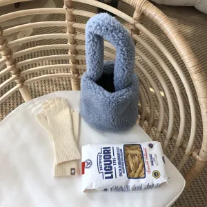Détail de sac à main pelucheux bleu douillet, mise en scène esthétique sur rotin.
