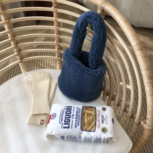 Vue détaillée d'un sac à main moelleux bleu douillet avec des gants en tricot sur chaise.