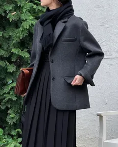 Vista detallada de la chaqueta de lana gris oscuro y la bufanda negra con flecos.