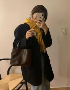 Primer plano de la suave bufanda de lana amarilla con flecos para look de otoño.