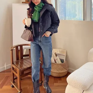 Detail view of a cozy green knitted cross wool scarf worn by model indoors, stylish accessory.