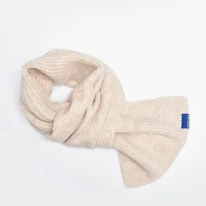 Close-up detail of beige ribbed knit cross wool scarf, warm winter neck warmer accessory.