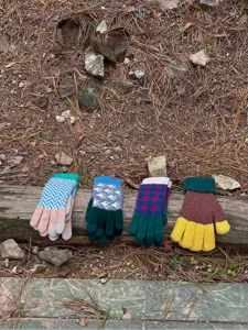 Detailed showcase of four colorful knitted winter gloves neatly displayed outdoors on a log.