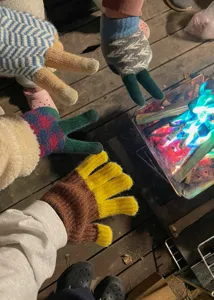 Detail shot of winter colorful knit gloves featuring cozy striped and color-block design outdoors.