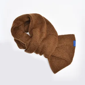 Detailed close-up of brown knitted cross scarf, soft woolen winter warmth style.
