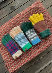 Detailed view of colorful winter knitted gloves with geometric patterns and cozy warm cuff.