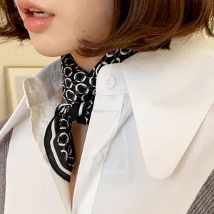 Close-up detail of a classic black and white patterned silk square scarf worn around the neck.