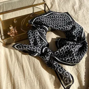 Detailed shot of a chic black and white printed square scarf, elegant neck and hair accessory.