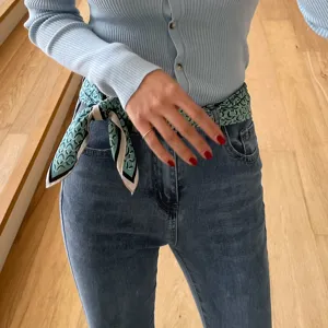 Detailed shot of a stylish printed silk scarf worn as a chic waist belt for modern women.