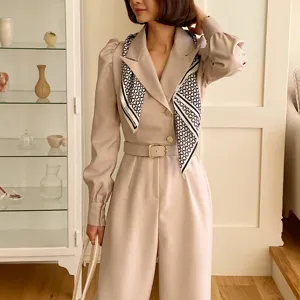 Stylish women's beige jumpsuit with matching patterned silk scarf for elegant daily wear.
