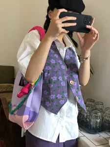 Detail shot of handmade knitted shoulder bag with colorful chain strap and floral vest outfit