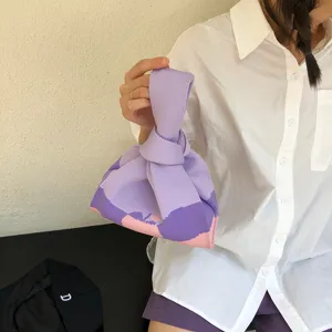 Knitted knot bag detail view, soft purple and pink color block handbag, casual daily carry.
