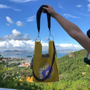 Sac cabas en tricot fait main avec motif de fleurs, poignée noire et lanière chaîne.