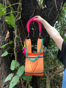 Close-up detail of knitted tote bag with bright orange fabric, pink handle and teal chain link.
