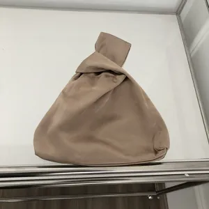 Detaillierte Nahaufnahme einer eleganten Satintasche mit Knoten in Taupe Farbe minimalistisch