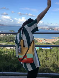 Knitted shoulder bag with colorful block design and chunky black chain strap for outdoor travel.
