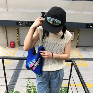 Vue détaillée du sac cabas en tricot avec bandoulière chaîne et joli pendentif dans une rue.
