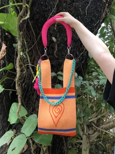 Handmade knit tote bag with vibrant orange and pink design, featuring chain and heart detail.