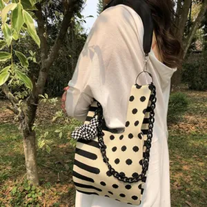 Detailansicht der stylischen Strick-Umhängetasche mit Punkten, Streifen und Kettengurt.
