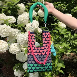 Schöne Strick-Tasche für Damen mit buntem Herz-Muster, grünem Griff und stylischer pinker Kette.