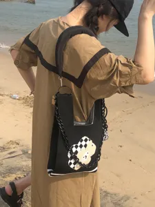 Vue détaillée d'un sac cabas en tricot noir avec joli motif d'ours et chaîne tendance.