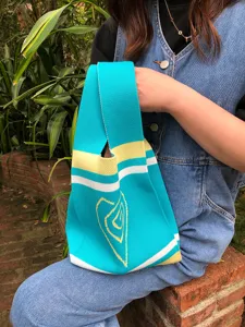 Detailed view of the colorful knitted tote bag, featuring turquoise, yellow, and white stripes.