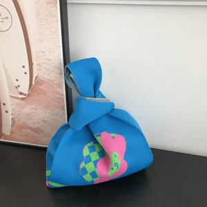 Detail de sac cabas en tricot bleu, joli motif rose, accessoire de mode tres chic.