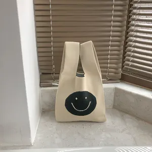Beigefarbene Strick Handtasche mit niedlichem schwarzen Smiley Gesicht Design für Alltag.