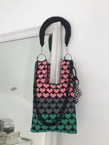 Detailed view of the colorful knit shoulder bag with heart pattern and chunky chain handle.