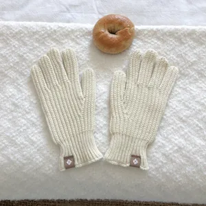 Vista detallada de acogedores guantes de punto crema con puños acanalados y etiquetas sutiles.