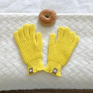 Detalle en primer plano de guantes de invierno de punto amarillo con etiqueta de cuero.