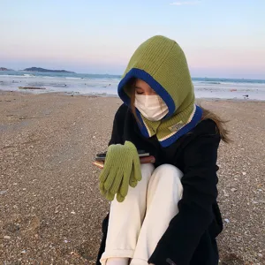 Closeup detail shot of the winter knitted hooded scarf and touchscreen gloves set in beach outdoor scene.